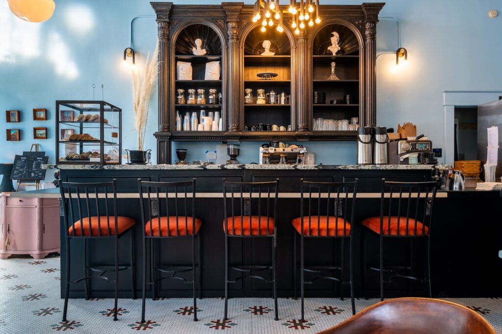 A black bar punctuates a retro-inspired restaurant with light-colored walls and a tiled floor