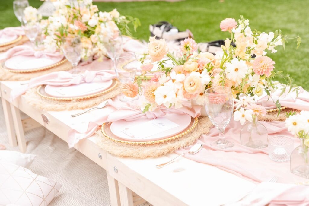 Pink, gold and white accents decorate a romantic table set for an outdoor event