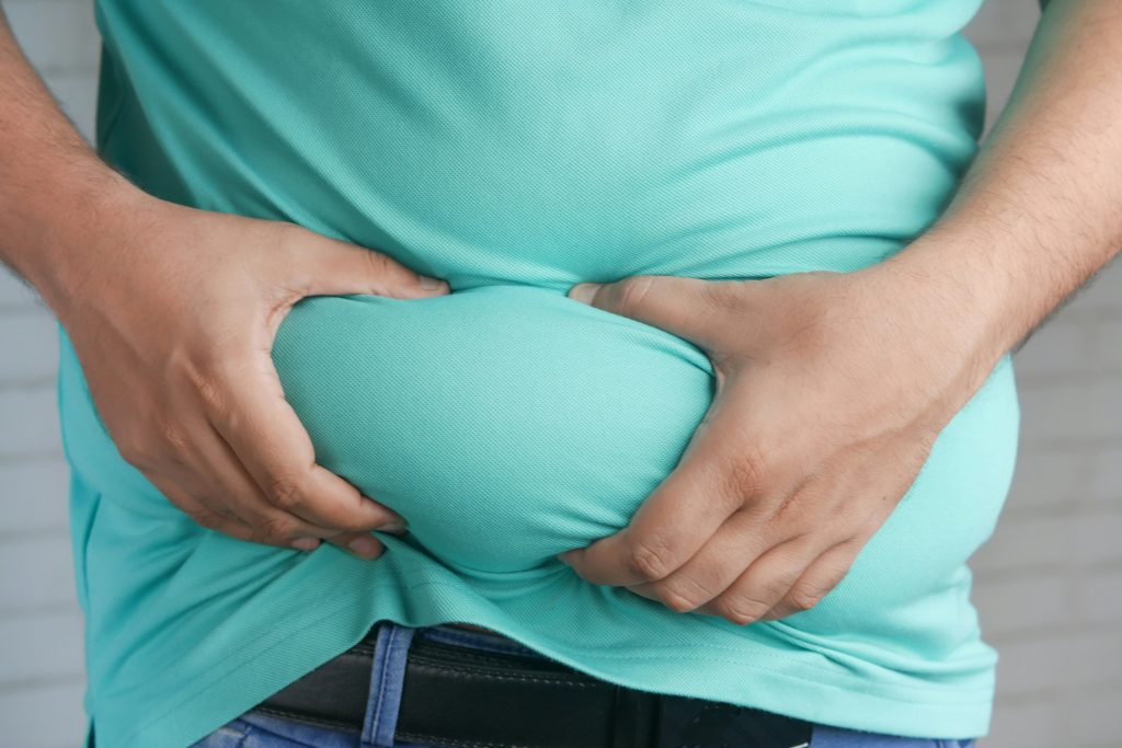 A person holds their stomach through a t-shirt