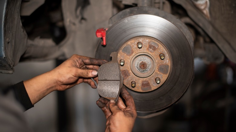 A mechanic showing a used brake pad next to the brake rotor